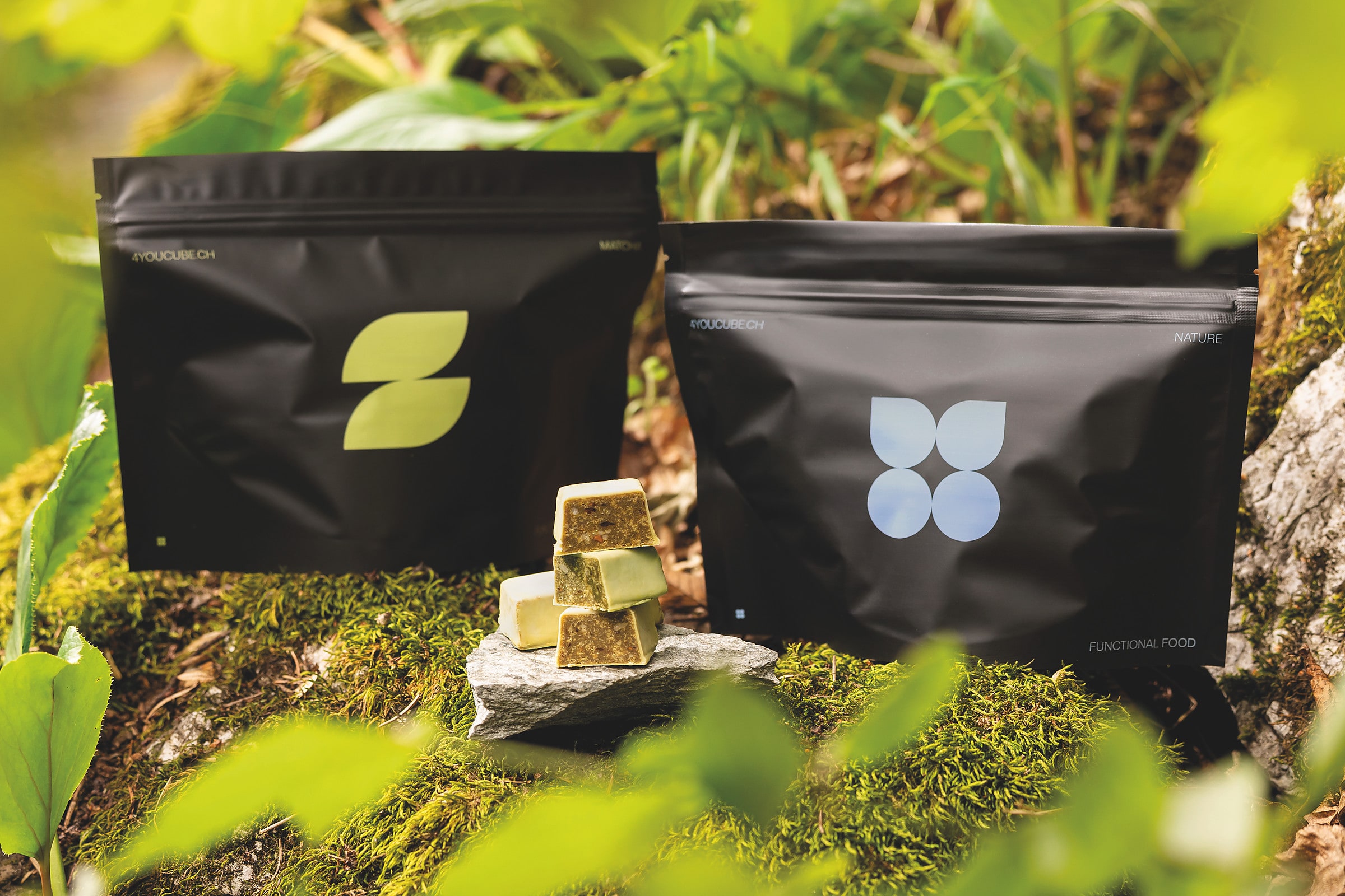 Die Packungen 4YOU CUBE Nature und Matcha mit Cubes auf einem bemoosten Stein im Wald